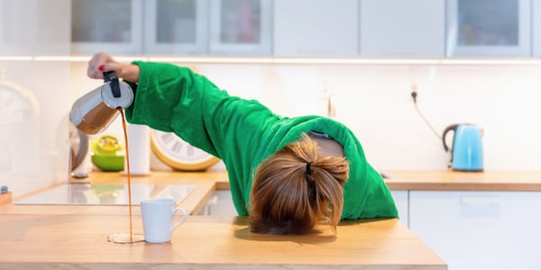 Femme qui verse son café à côté de la tasse la tête contre la table