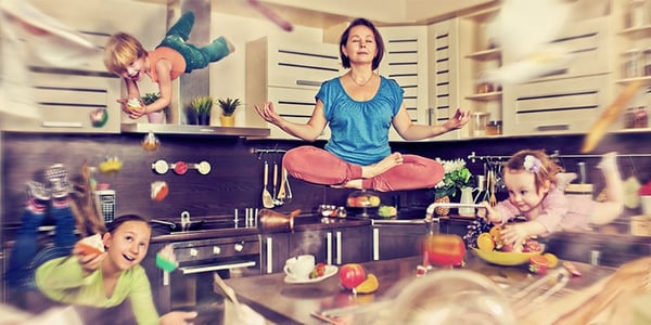 Femme qui lévite dans la position du lotus dans une cuisine avec 3 enfants en action autour d'elle