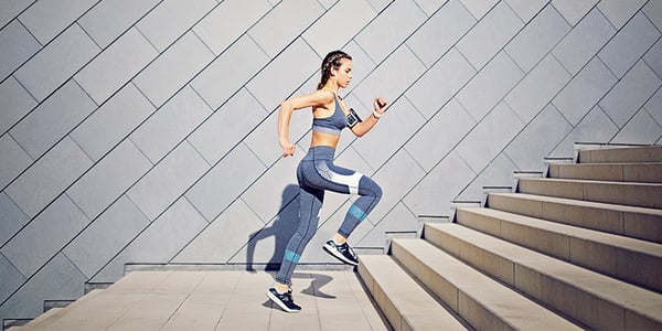 Femme en vêtements de sport qui monte des escaliers dans un mouvement de course