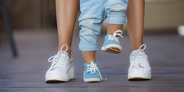 enfants debout sur un pied entre les pieds d'un adulte