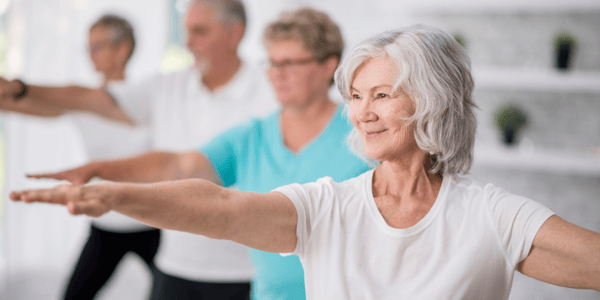 Femme dans un groupe d'activité physique avec les bras levés à l'horizontale