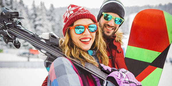 Homme et femme qui tiennent des ski