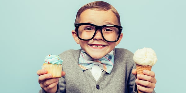 Enfant qui tient un gâteau dans la main droite et un cornet de crème glacée dans la main gauche