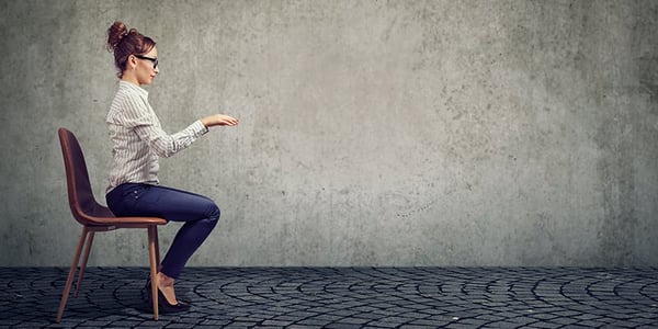 Femme assise sur une chaise qui mime la position pour taper sur un clavier d'ordinateur