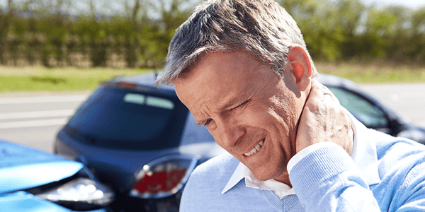 Homme qui tient son cou devant une voiture