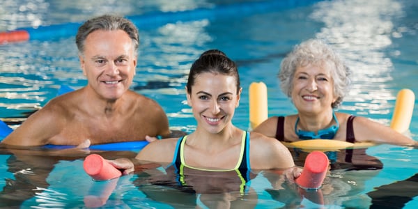 Femmes et homme dans une piscine avec accessoires d'exercice