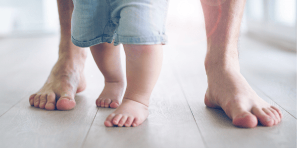 Enfant debout entre les pieds d'un adulte