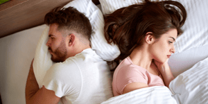 Homme et femme couchés dos à dos dans un lit