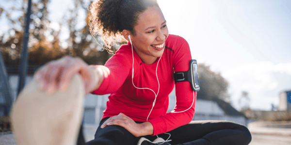 Femme en vêtements de sport assise au sol dans un exercice d'étirement