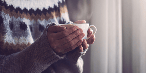 Personne qui tient une boisson chaude dans une tasse