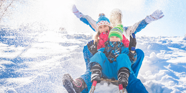Homme, femme et enfant sur un traineau qui descendent une cote de neige