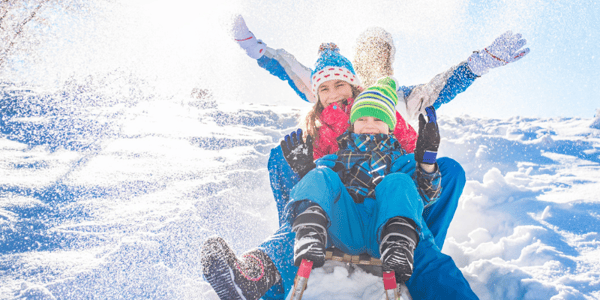 Homme, femme et enfant sur un traineau qui descendent une cote de neige