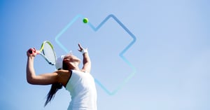 A female tennis player in mid-serve motion under a clear blue sky, highlighting shoulder extension and athletic posture.