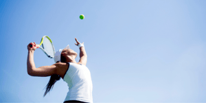 Femme en vêtements de sport qui s'apprête à frapper une balle de tennis avec sa raquette