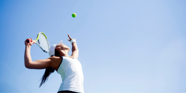 Femme en vêtements de sport qui s'apprête à frapper une balle de tennis avec sa raquette