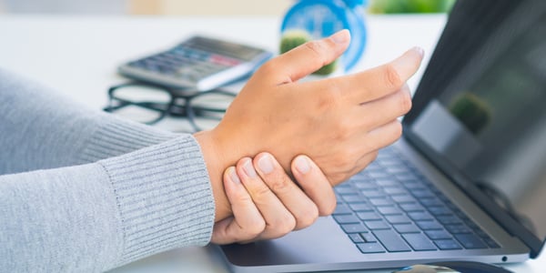 Personne qui tient son poignet au dessus d'un clavier d'ordinateur